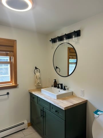 Bathroom with light walls and a dark green vanity
